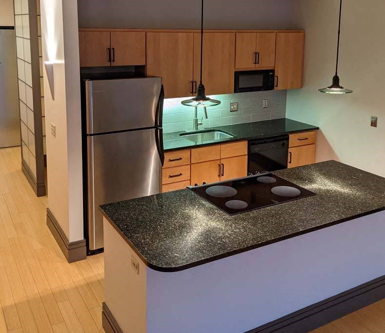 a kitchen with a stove top oven next to a refrigerator at Flats at Southside, Pittsburgh Pennsylvania
