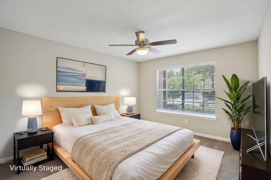 A bedroom with a bed, a ceiling fan, and a painting on the wall.