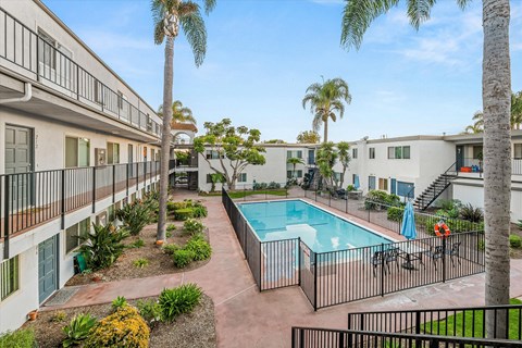 Central pool area with tropical landscaping and seating at Shorehaven Townhomes Apartments, California, 93004