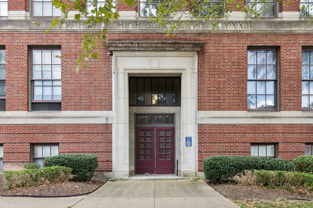 A red brick building with a white arched entrance and a blue handicap sign.