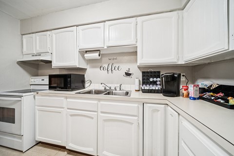 A white kitchen with a coffee sign on the wall.