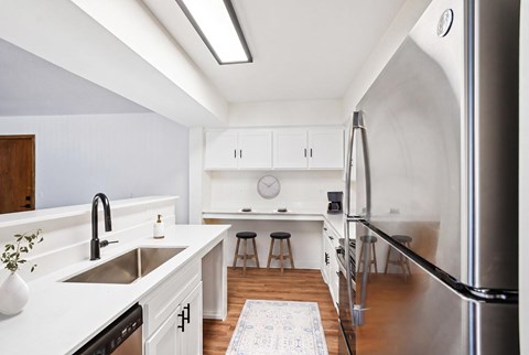 A modern kitchen with white cabinets and a stainless steel refrigerator.