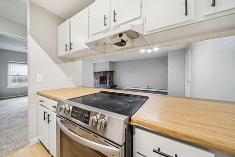 A modern kitchen with a stove top oven and white cabinets.