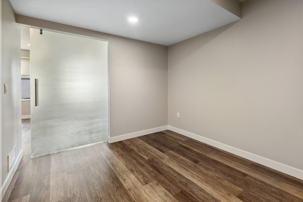 an empty room with wood flooring and a sliding glass door at The Rowe, Grand Rapids, 49503