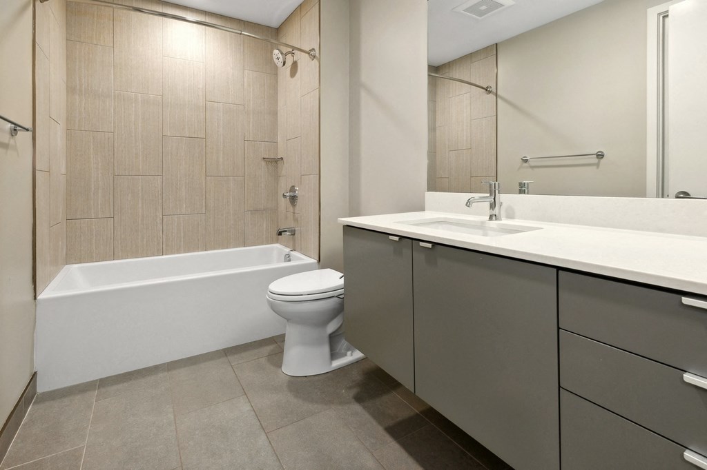 a bathroom with a toilet and a sink and a bath tub at The Rowe, Grand Rapids, 49503