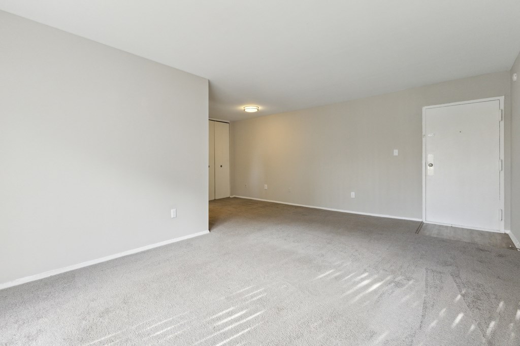 an empty living room with white walls and carpet at Briarwood Apartments, Dumfries, VA
