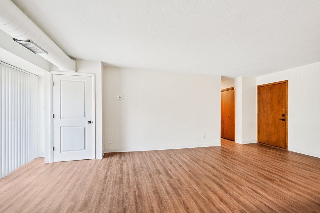 A room with a white door and wooden floors.