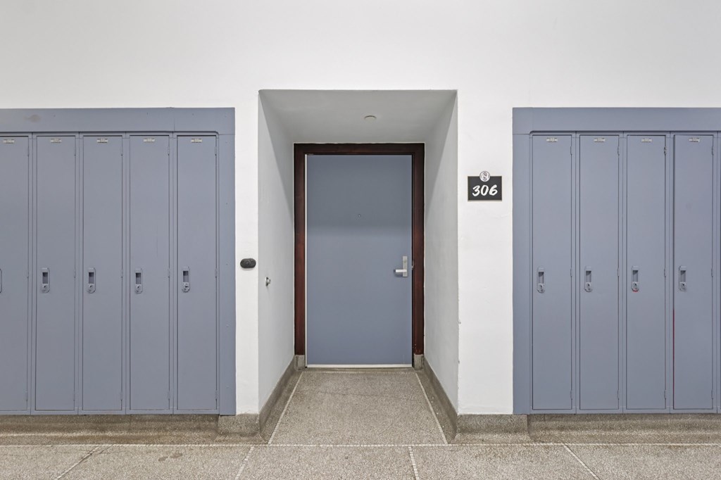 A set of blue lockers are on either side of a door with a number 306 above it.