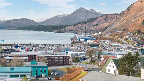 A small town with a large body of water and mountains in the background.