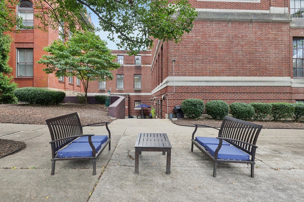 A park area with a bench, table and a tree.