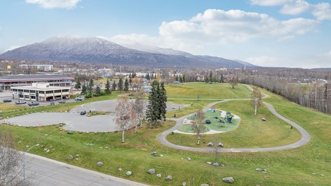 A park with a playground and a mountain in the background.