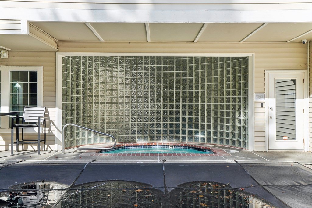 A jacuzzi with a glass block wall behind it.