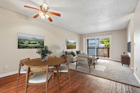 A dining room with a table and chairs and a painting on the wall.