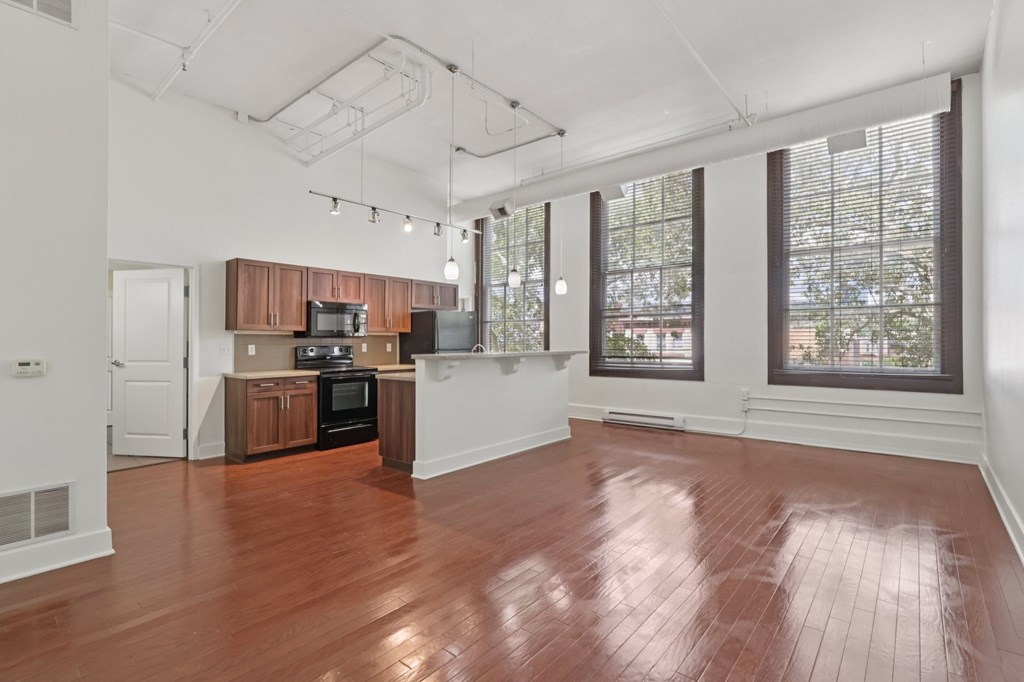 A large living room and kitchen with wooden floors and white walls.