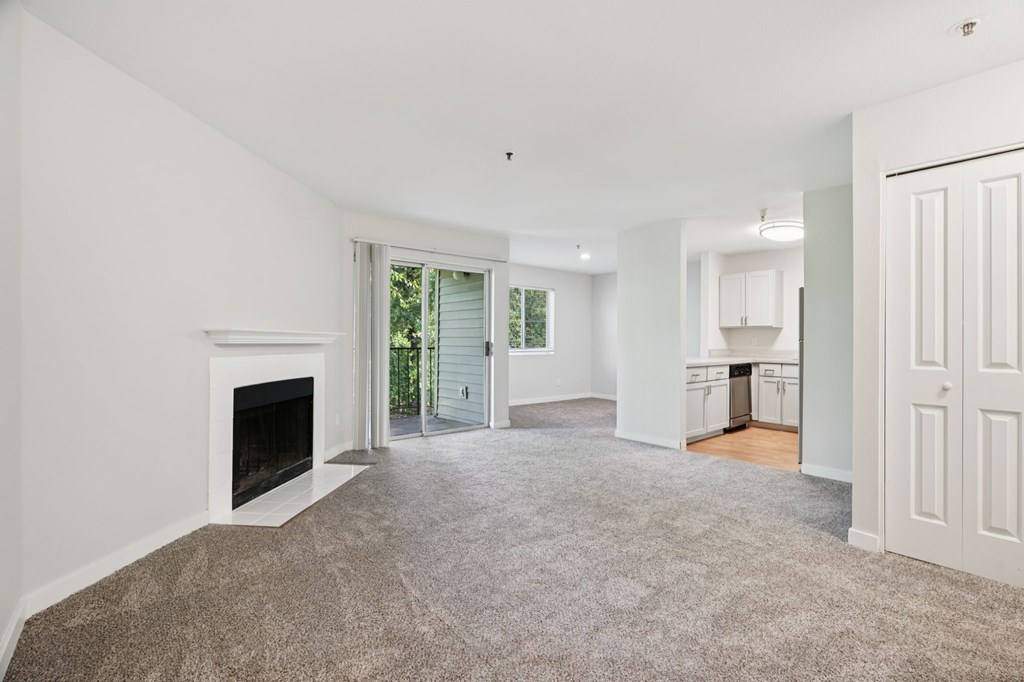 A spacious living room with a fireplace and carpeted floor.
