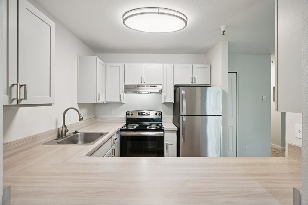 A modern kitchen with stainless steel appliances and wooden flooring.