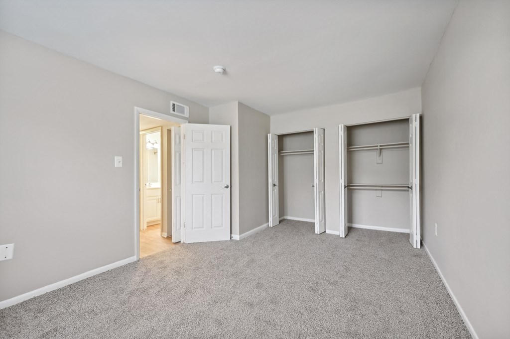 a bedroom with a carpeted floor and two closet doors at ReNew Odenton