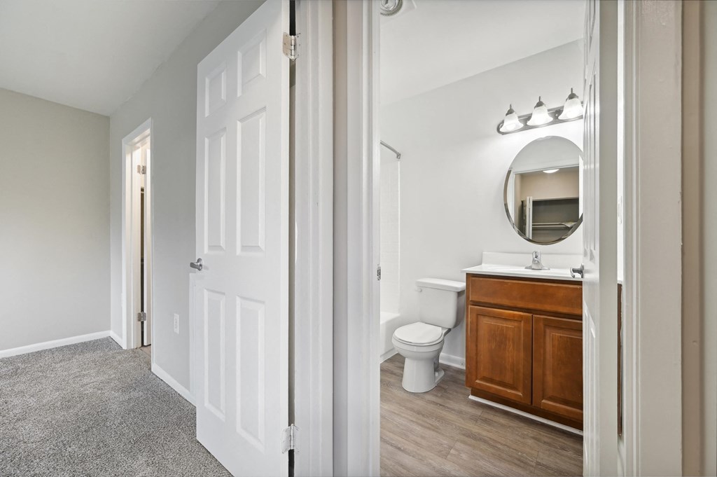 a bathroom with a toilet and a vanity with a mirror at ReNew Odenton