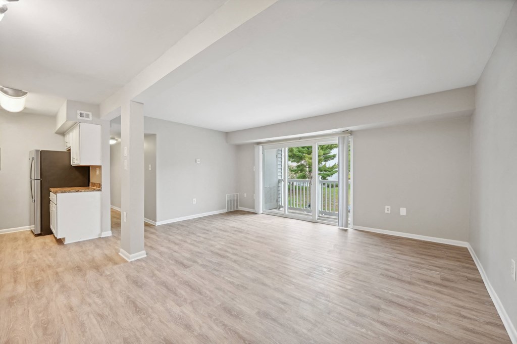 an empty living room with a sliding glass door to a balcony at ReNew Odenton
