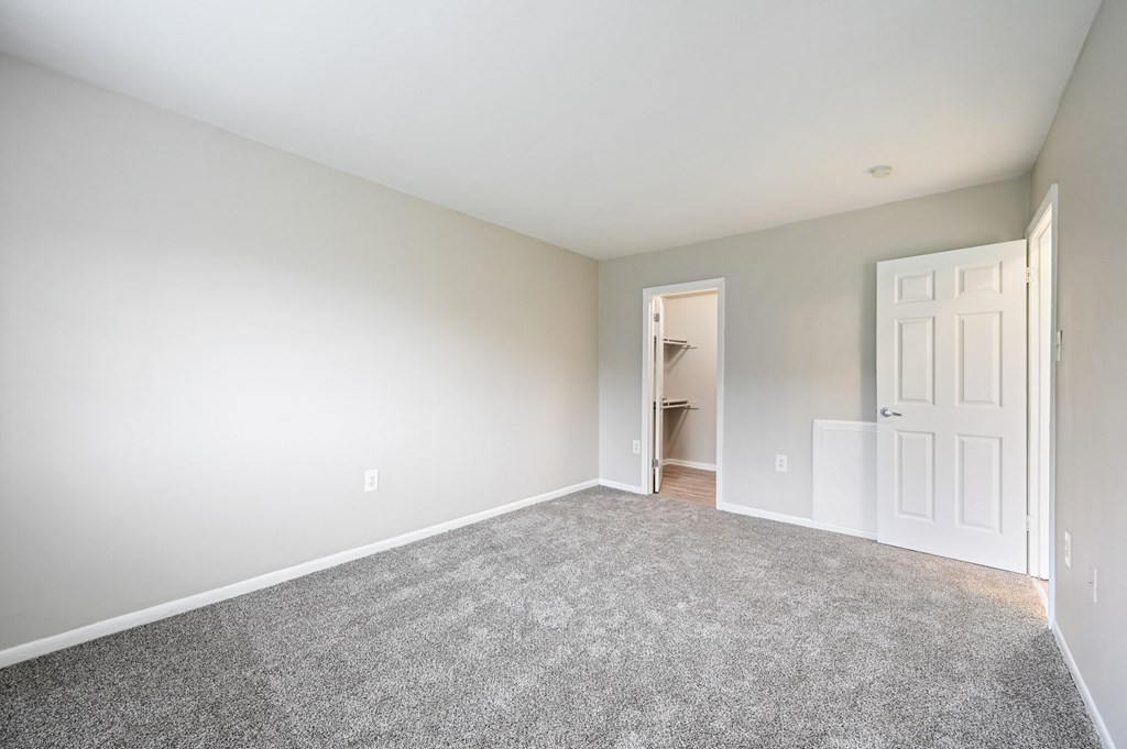 an empty bedroom with carpet and a door to a closet at ReNew Odenton