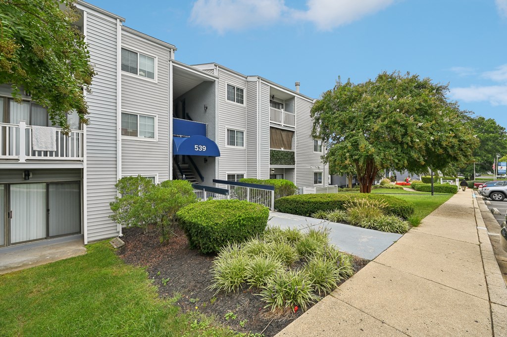 Exterior view of our apartments with a sidewalk and landscaping in front at ReNew Odenton