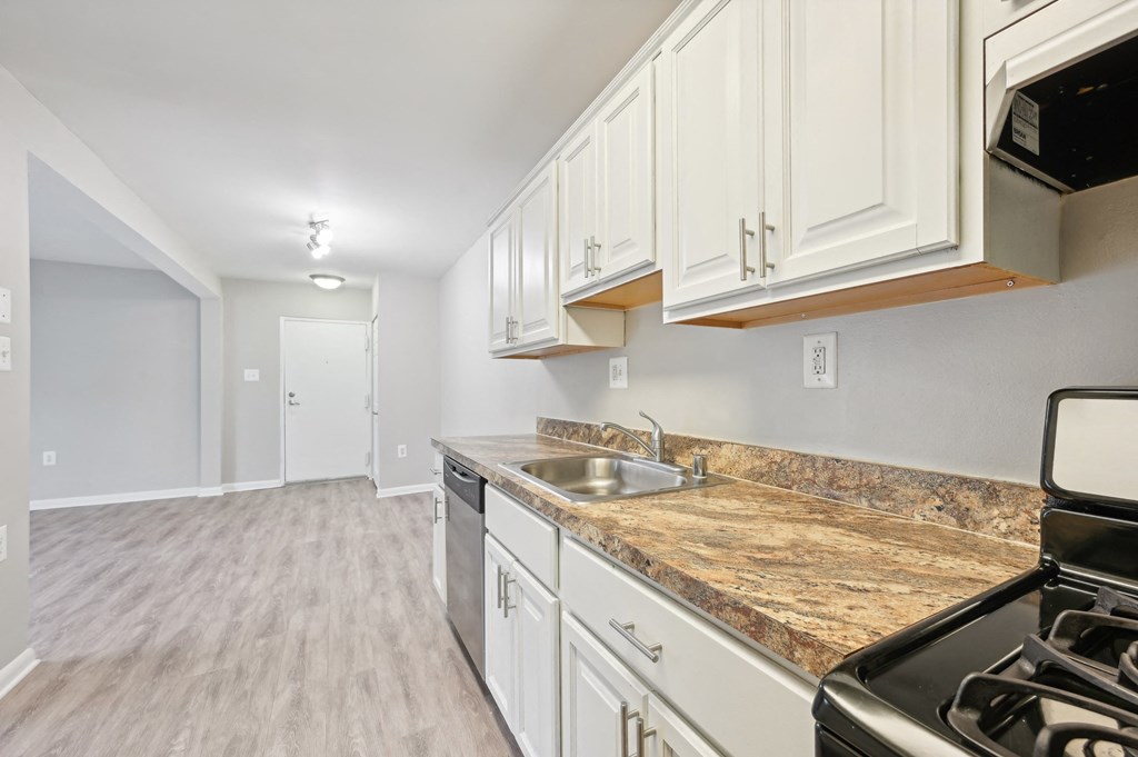 an empty kitchen with white cabinets and granite counter tops and a stove and microwave at ReNew Odenton