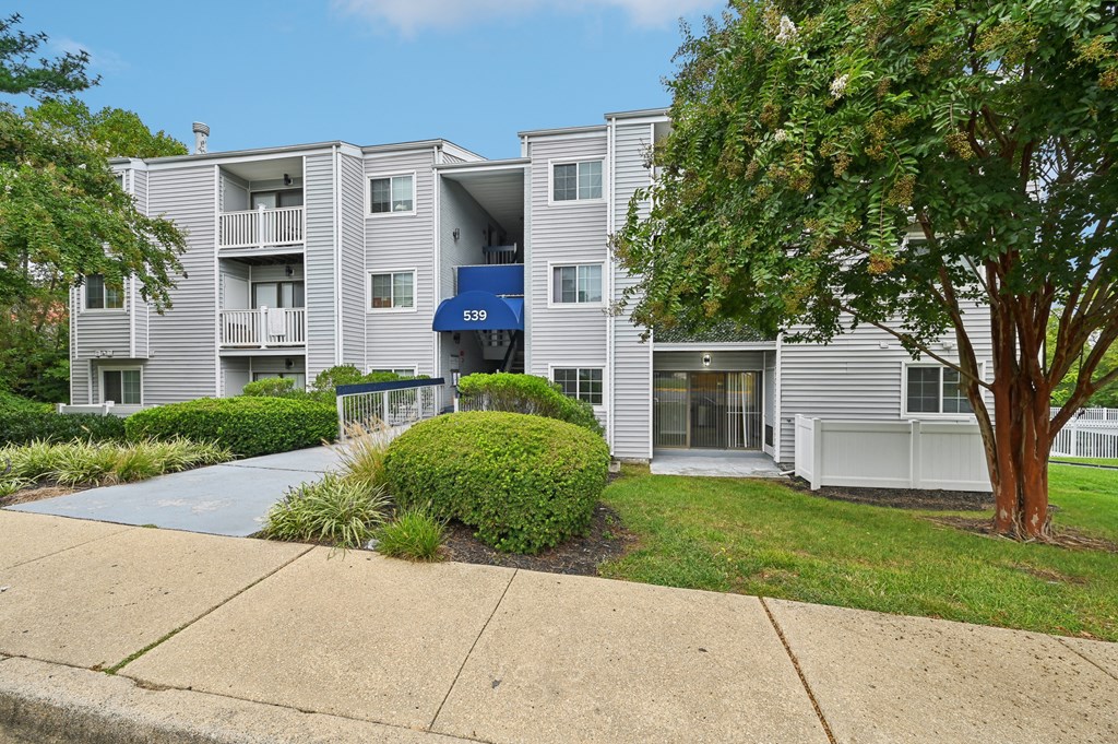 an apartment building with white siding and a sidewalk at ReNew Odenton