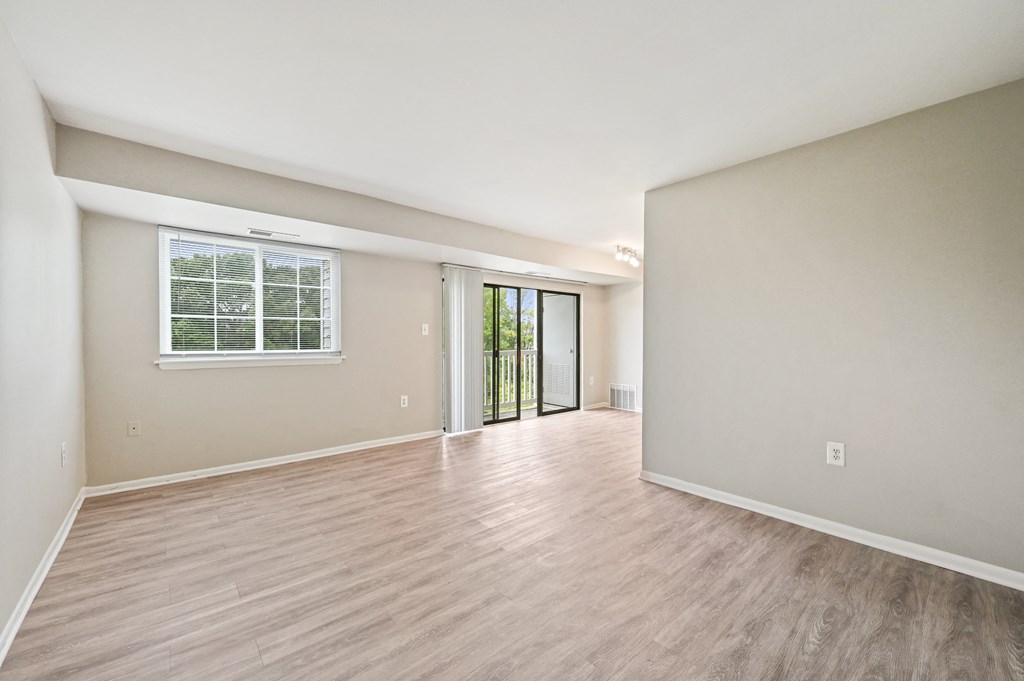 the living room and dining room of an empty house with wood flooring at ReNew Odenton