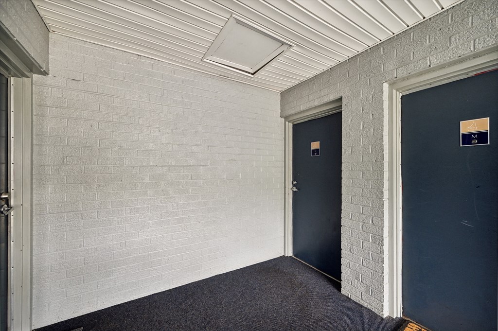 a hallway with two blue doors and a white brick wall at ReNew Odenton