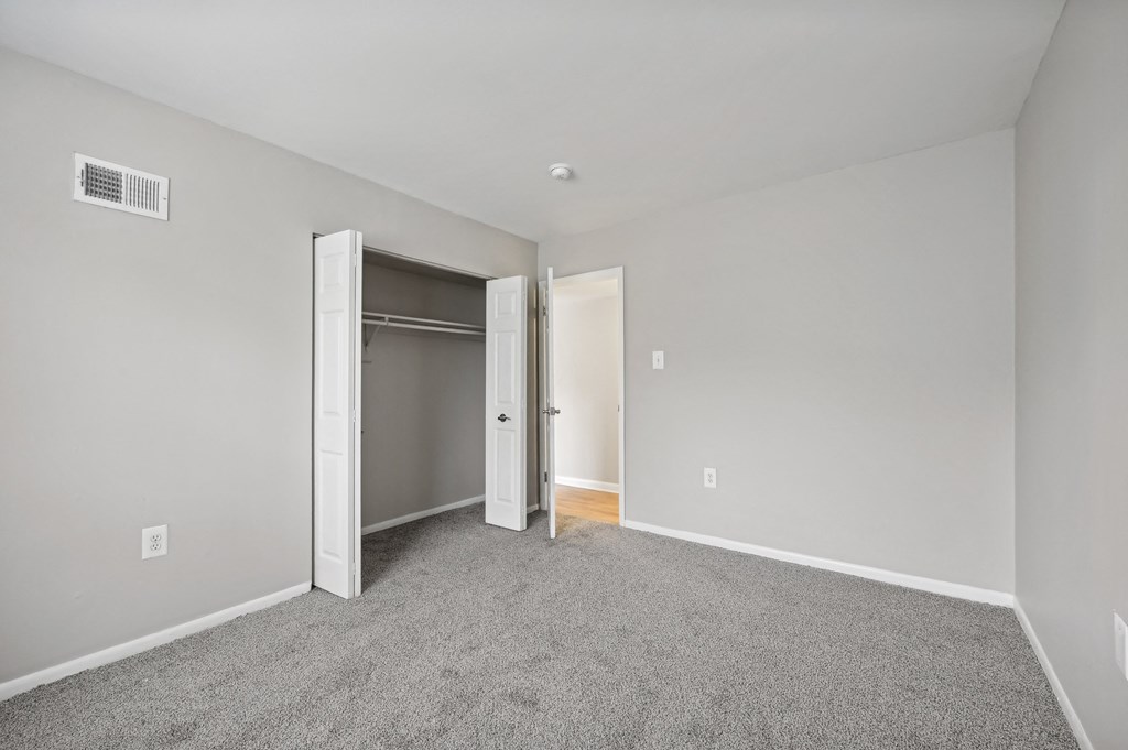 a bedroom with carpet and an open door to a closet at ReNew Odenton