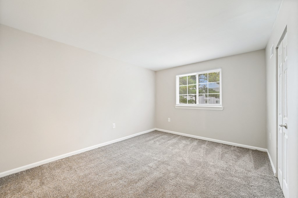 an empty bedroom with carpet and a window at ReNew Odenton