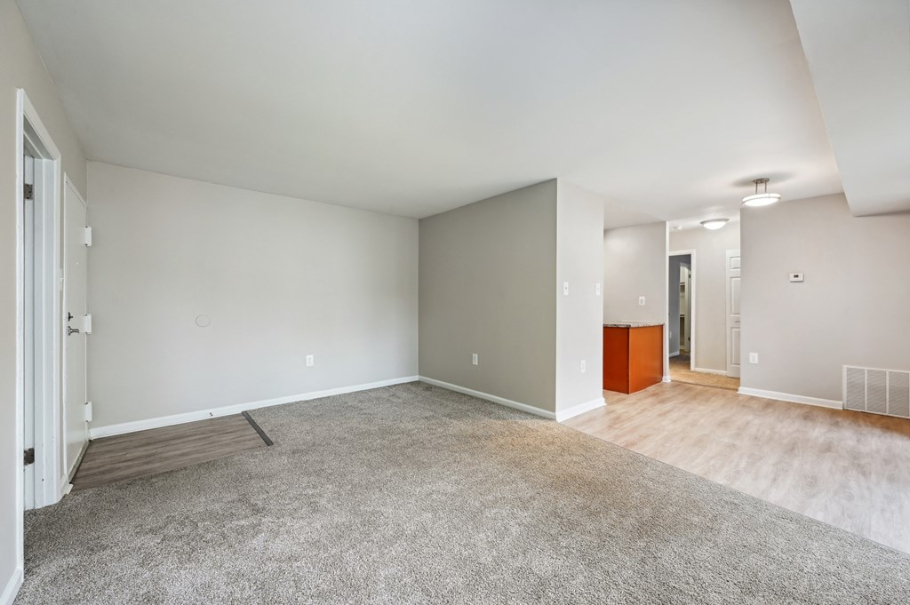 the living room and dining room in a new home with white walls and wood floors at ReNew Odenton