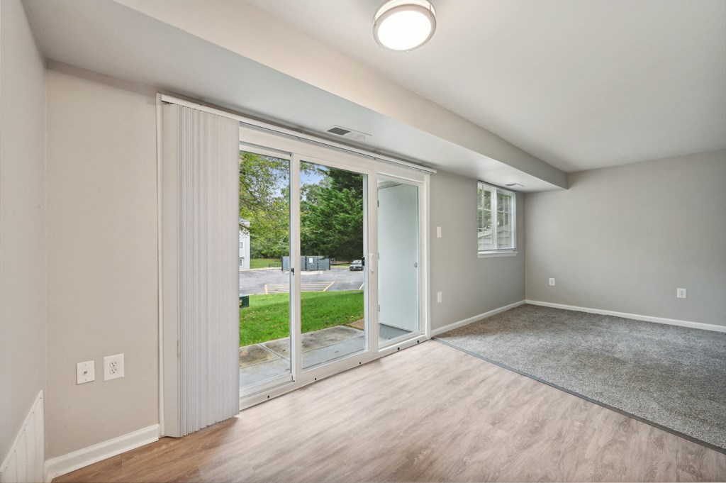 an empty living room with sliding glass doors to a yard at ReNew Odenton