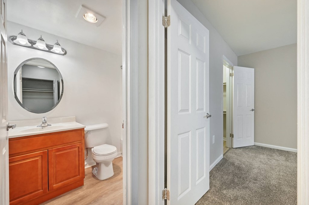 view into a bathroom with a mirror, a toilet and a sink from a hallway at ReNew Odenton