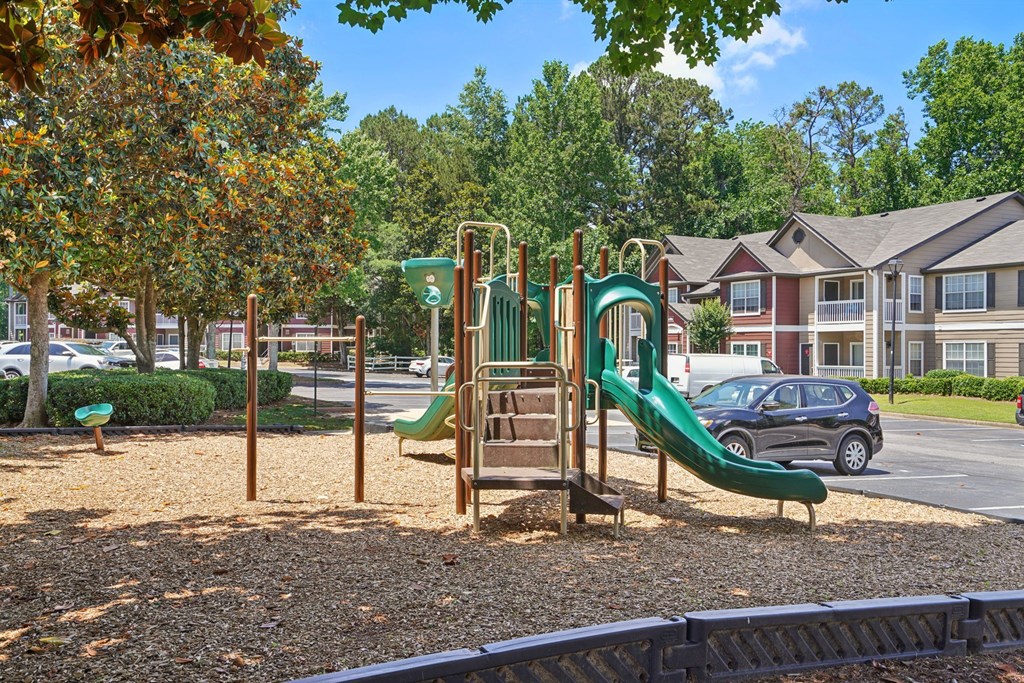 A playground with a green slide and a brown structure.