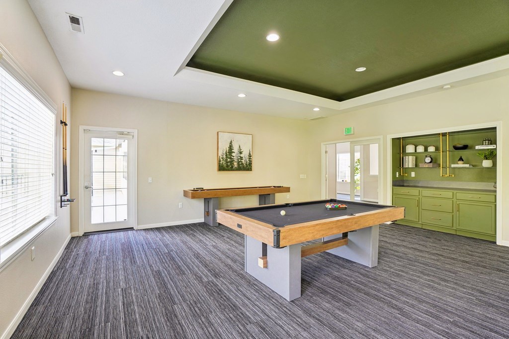 A room with a pool table and a green cabinet.