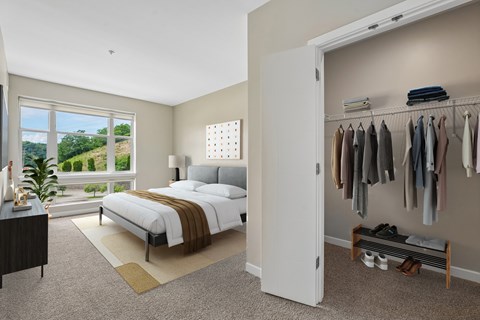 A bedroom with a large bed and a closet with clothes hanging.
