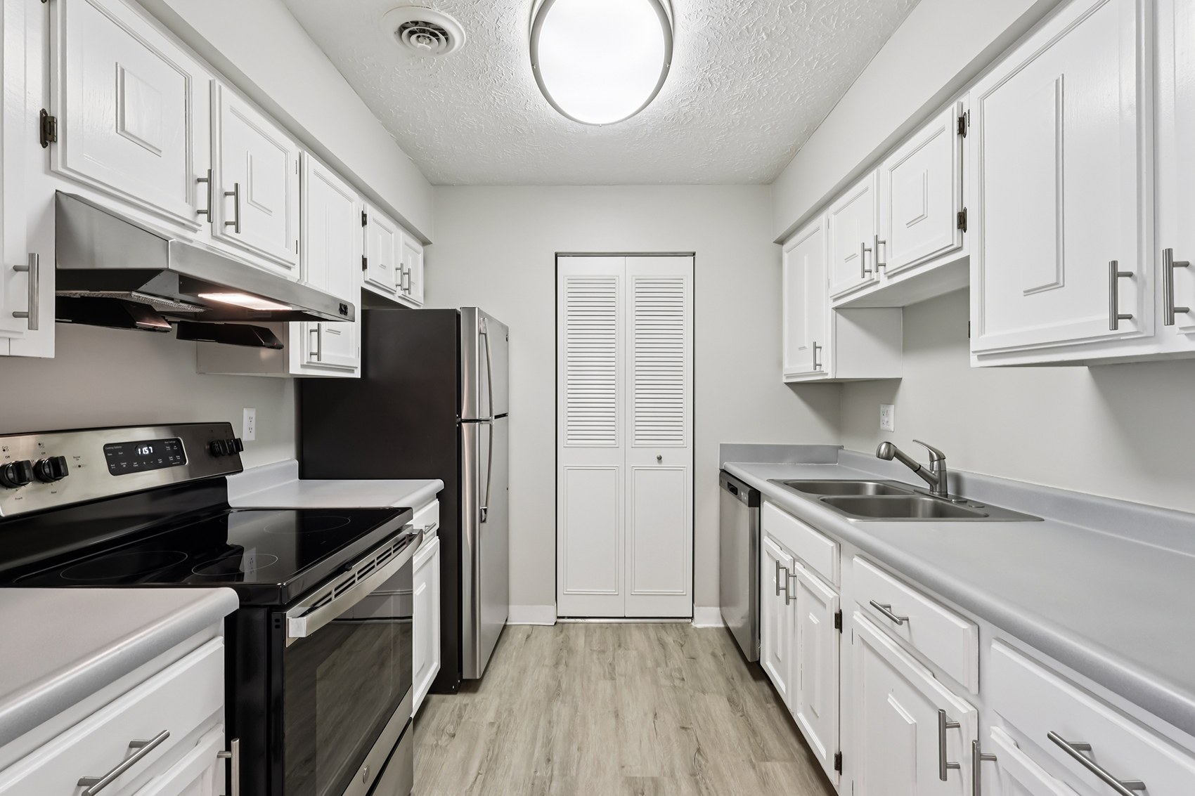 A kitchen with white cabinets and black countertops.