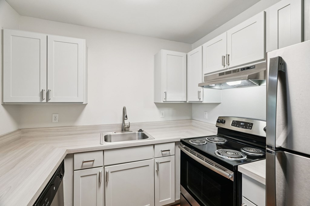 A kitchen with white cabinets and appliances.