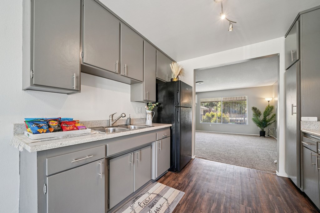 A kitchen with a black refrigerator and wooden floors.