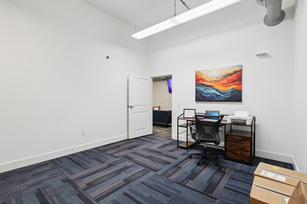 A business center with a carpeted floor and a painting on the wall.
