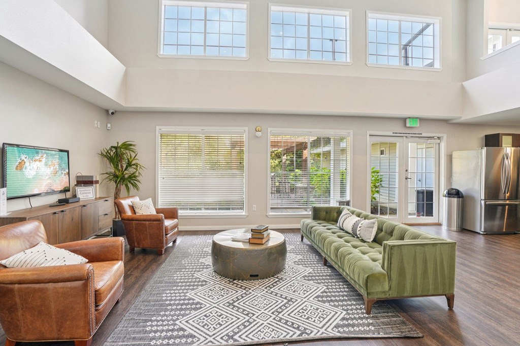 A sitting room with a brown leather couch, a green sofa, and a coffee table in the center.