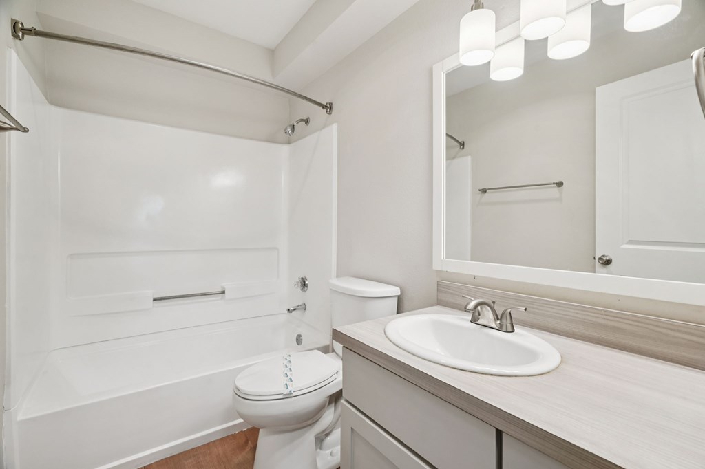 A white bathroom with a toilet, sink, and mirror.