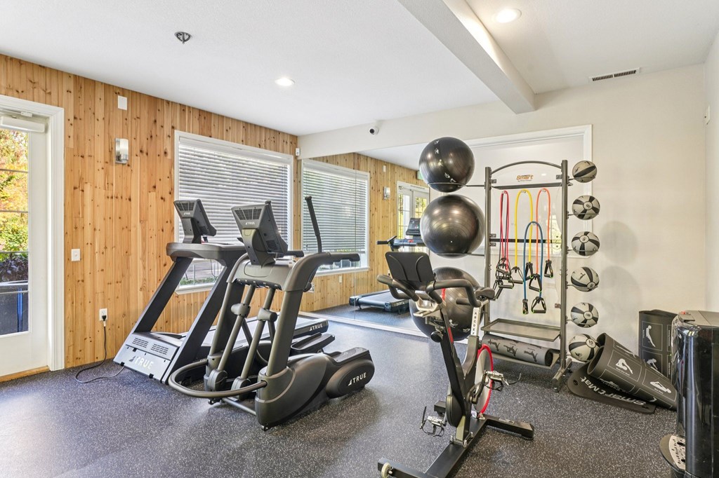 A fitness center with a treadmill, exercise bike, and weights.