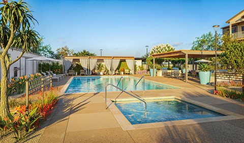 A pool surrounded by a concrete patio and a white fence.