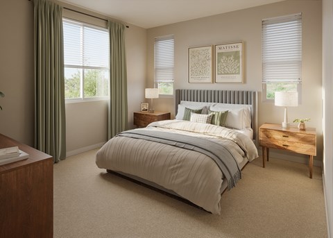 A bedroom with a large bed, a nightstand, and a window with curtains.