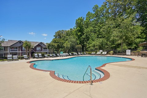 A large swimming pool surrounded by trees and chairs.