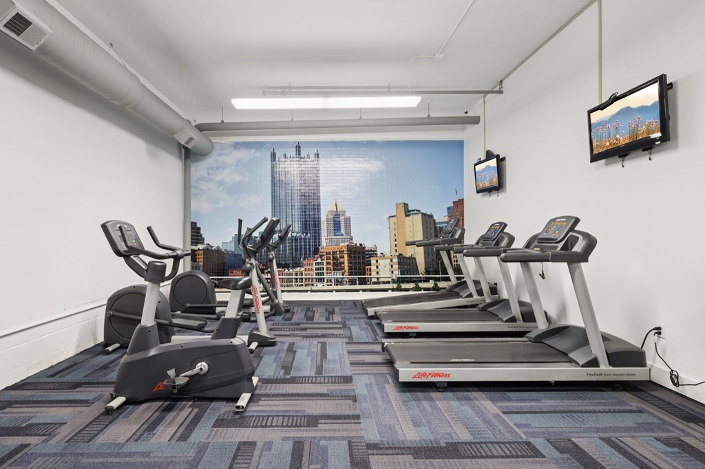 A gym with treadmills and a city view on the wall.