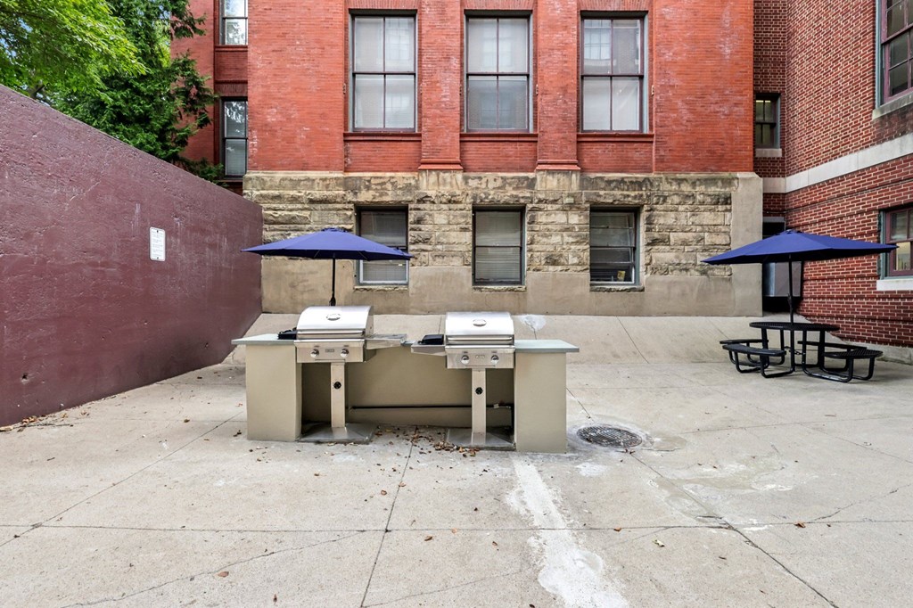 Picnic tables and umbrellas are set up on a concrete patio.