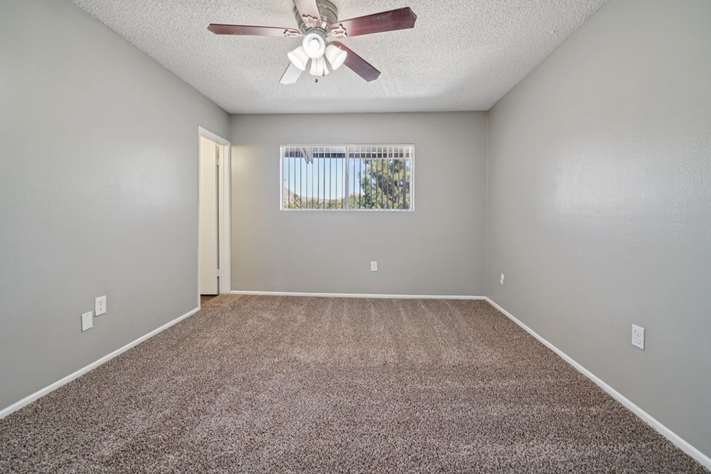 A room with a ceiling fan and carpeted floor.